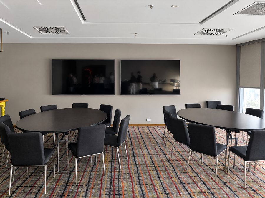Breakout room with two oval tables and wall mounted screens