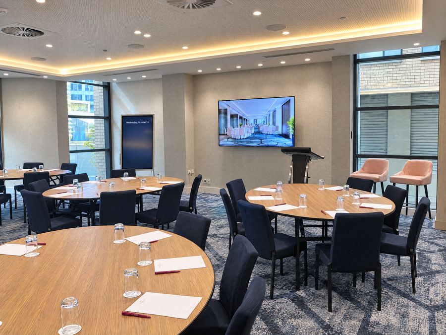 Function room set cabaret style, round tables with the side facing the screen and lectern left open