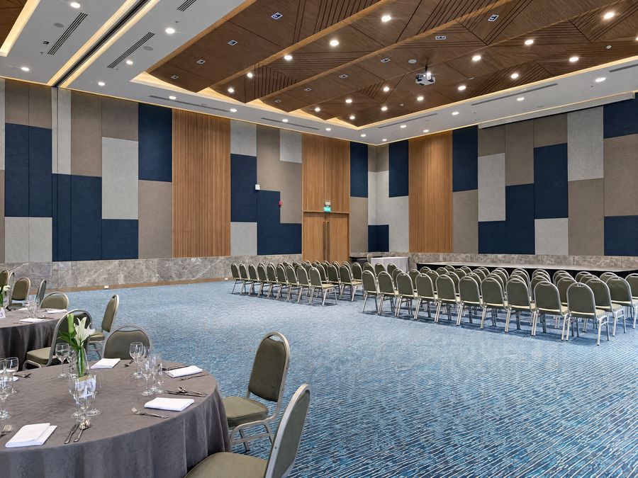 Ballroom set with theatre rows facing a stage at one end and dressed dinner rounds at the other