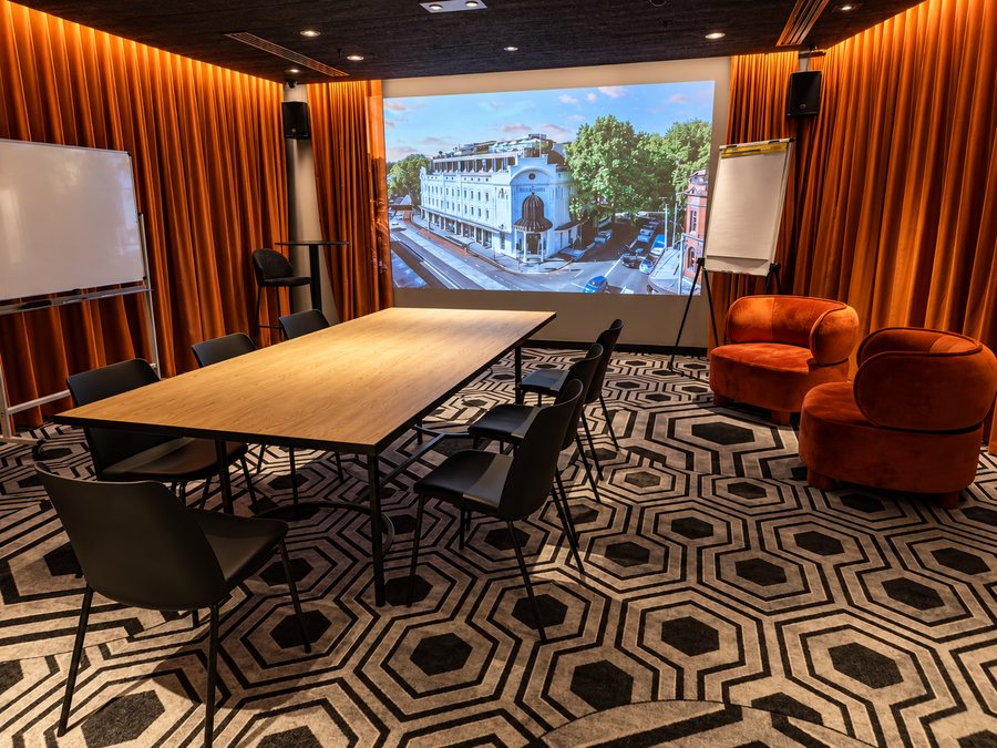 25hours Hotel The Olympia, meeting room with a boardroom table, projection screen and velvet lounge chairs