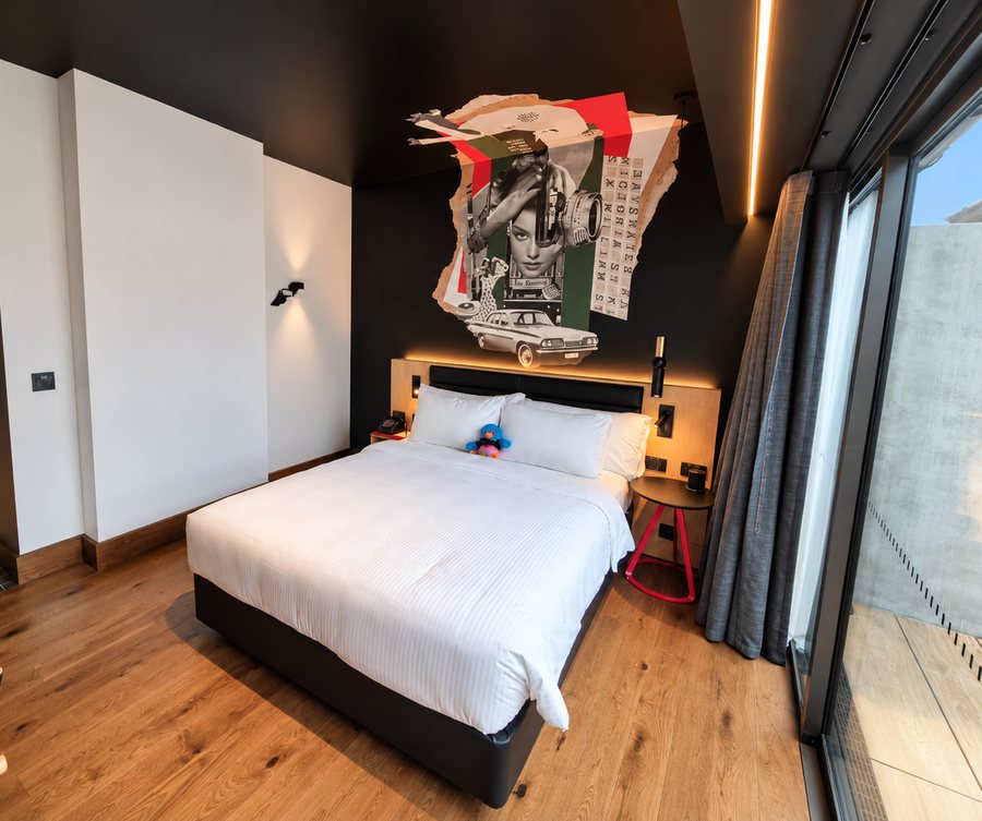 25hours Hotel The Olympia, guest room with a collage mural above the bed