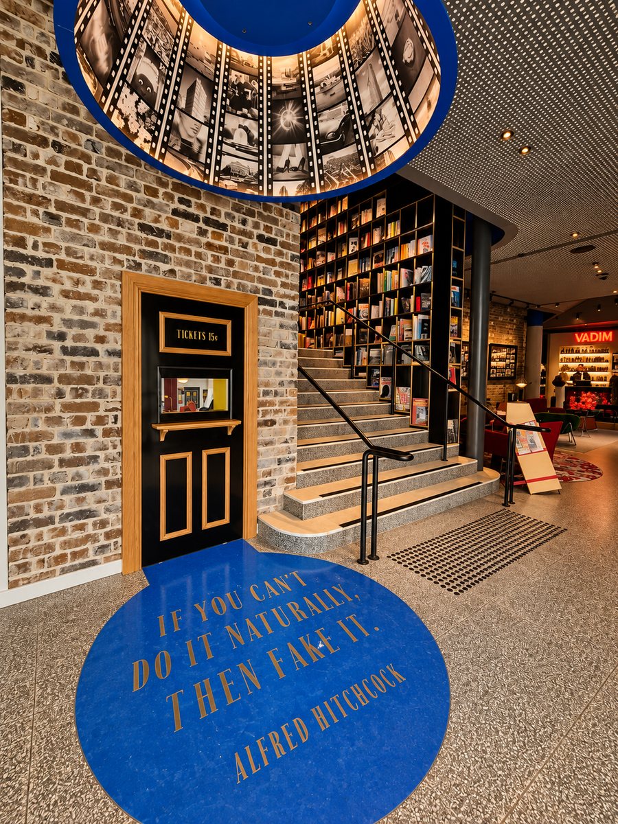 25hours Hotel The Olympia, entrance with a cinema ticket door and a book lined staircase