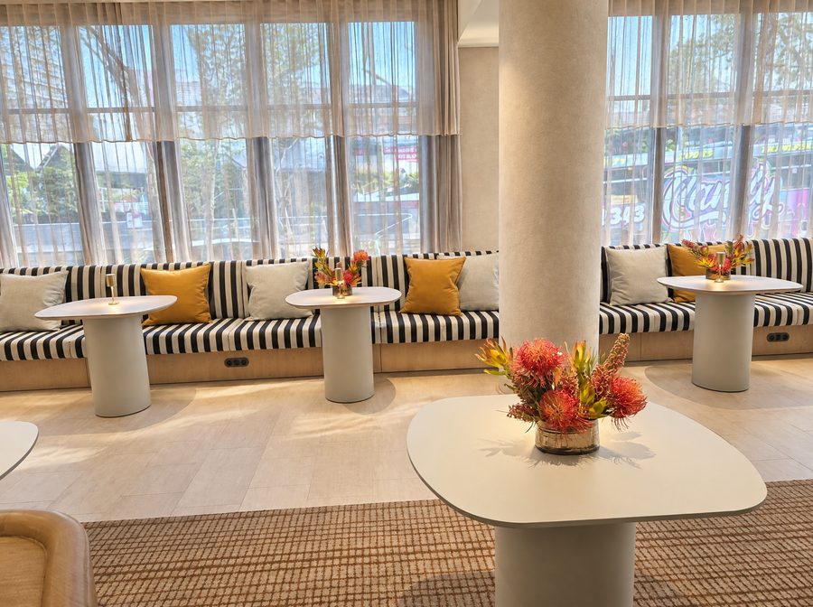 Adina Sydney Darling Harbour, restaurant with a striped banquette along the windows, round tables and orange cushions