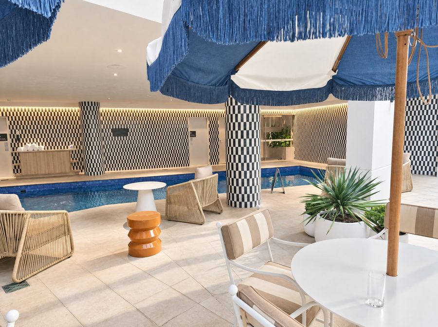 Adina Sydney Darling Harbour, pool deck with blue fringed umbrellas, woven lounge chairs and black and white checked tile columns