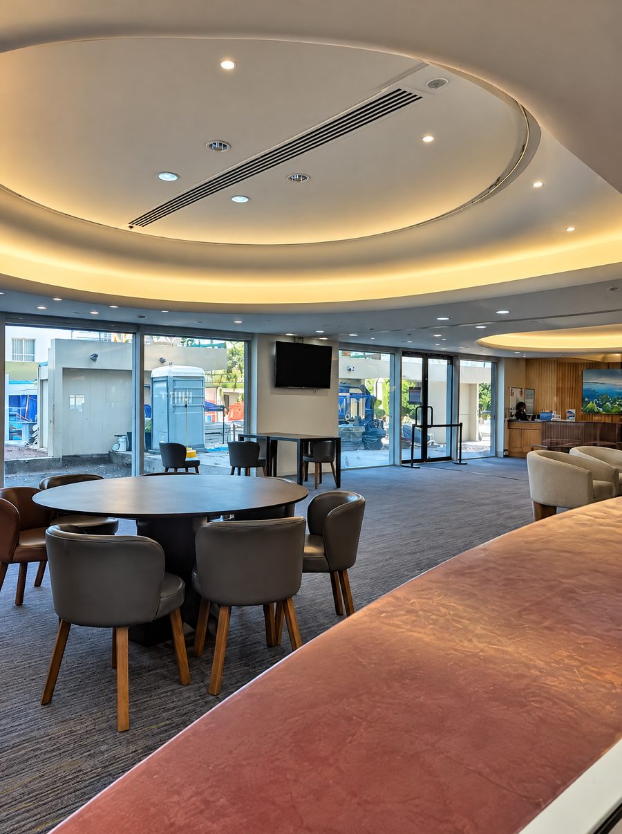 DoubleTree by Hilton Esplanade Darwin, lounge with a round table and leather chairs under a lit oval ceiling, glass walls to the forecourt