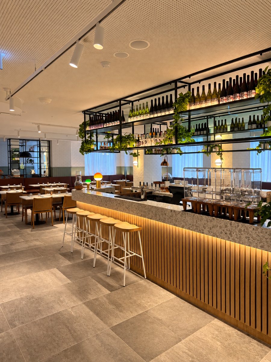 Holiday Inn Melbourne Bourke Street Mall, bar with a terrazzo counter, a lit timber slat front and bottle shelving hung with trailing plants