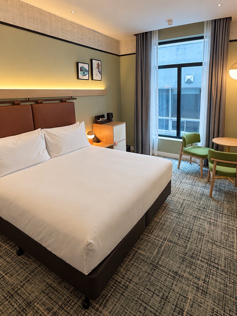 Holiday Inn Melbourne Bourke Street Mall, guest room with a leather headboard, sage walls and two green chairs by the window