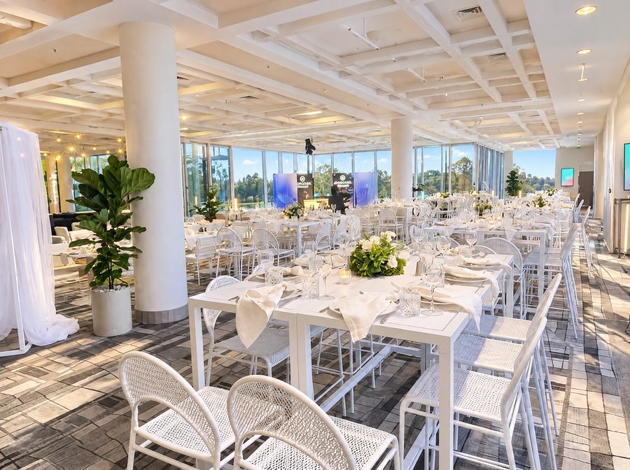 JW Marriott Gold Coast Resort & Spa, function room set with long white tables and white chairs, floor to ceiling windows along two sides looking out to trees