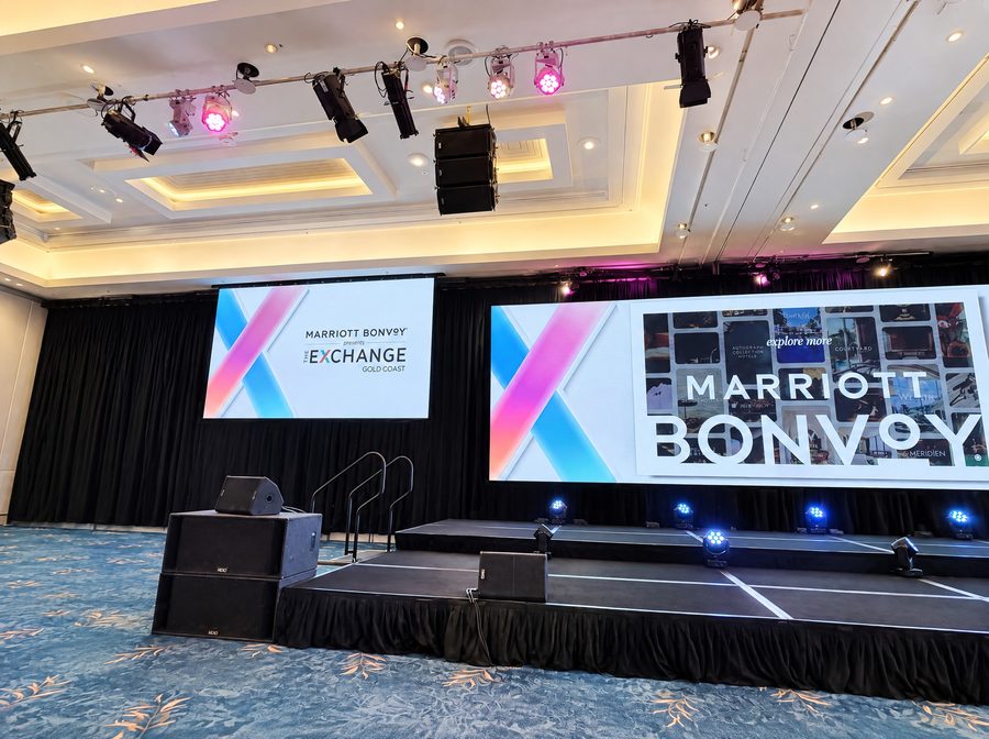 JW Marriott Gold Coast Resort & Spa, ballroom set for a plenary, a black draped stage with twin screens under a lighting rig