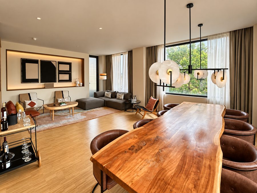 Kimpton Aysla Mallorca, suite living room with a live edge dining table for eight and a lounge beyond
