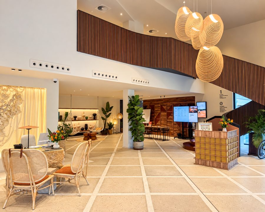 Kimpton Aysla Mallorca, double height lobby with rattan pendants and a curved timber staircase