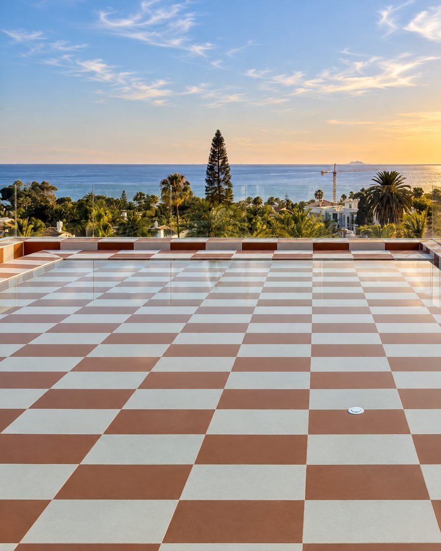 Kimpton Los Monteros Marbella, rooftop terrace with a checkerboard floor looking over palms to the sea at sunset