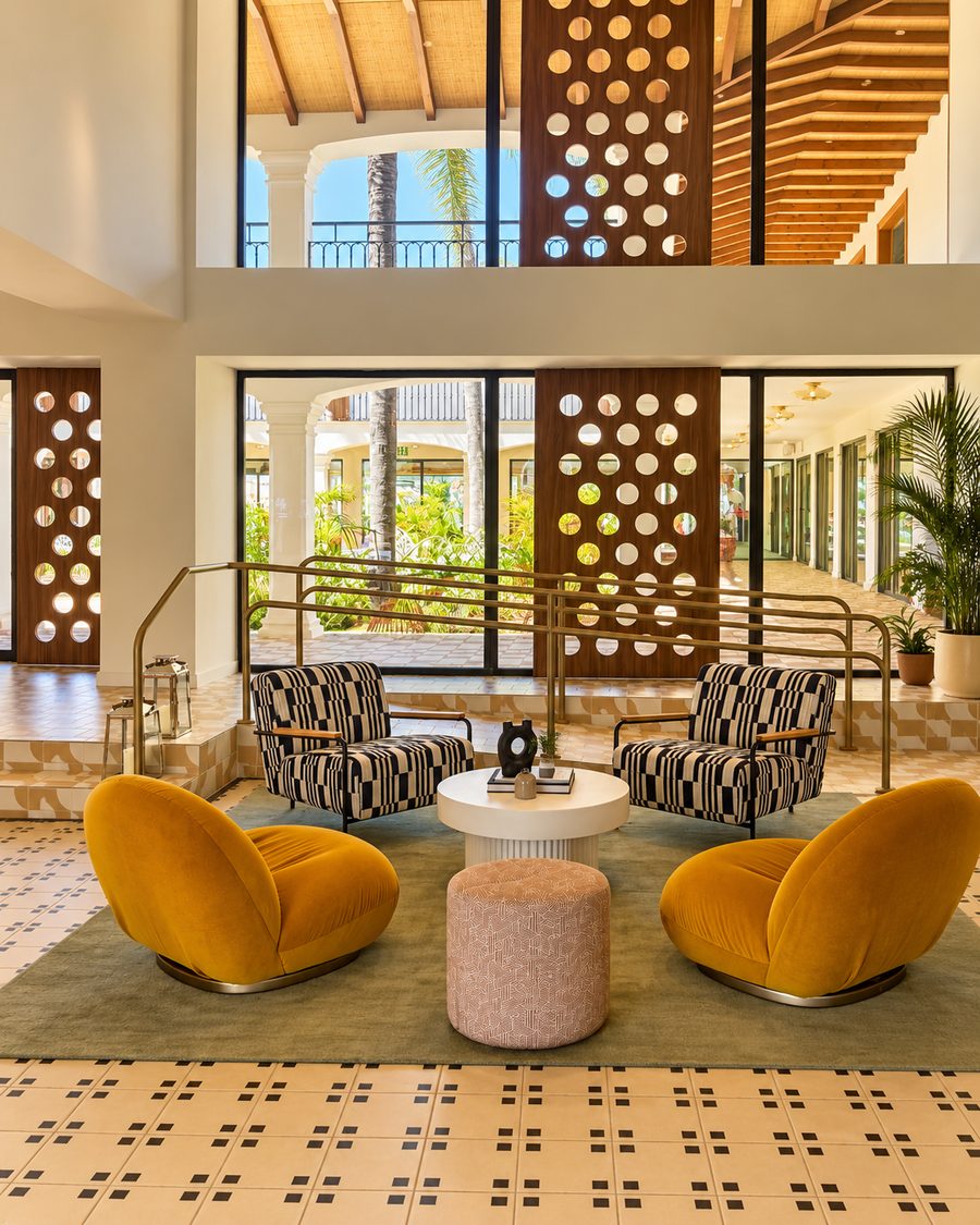 Kimpton Los Monteros Marbella, double height lobby with mustard velvet chairs and timber screens cut with circles