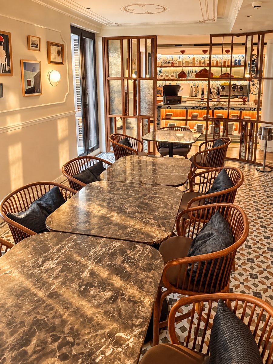Kimpton Vividora Barcelona, dining room with marble topped tables, bentwood armchairs and a patterned tile floor
