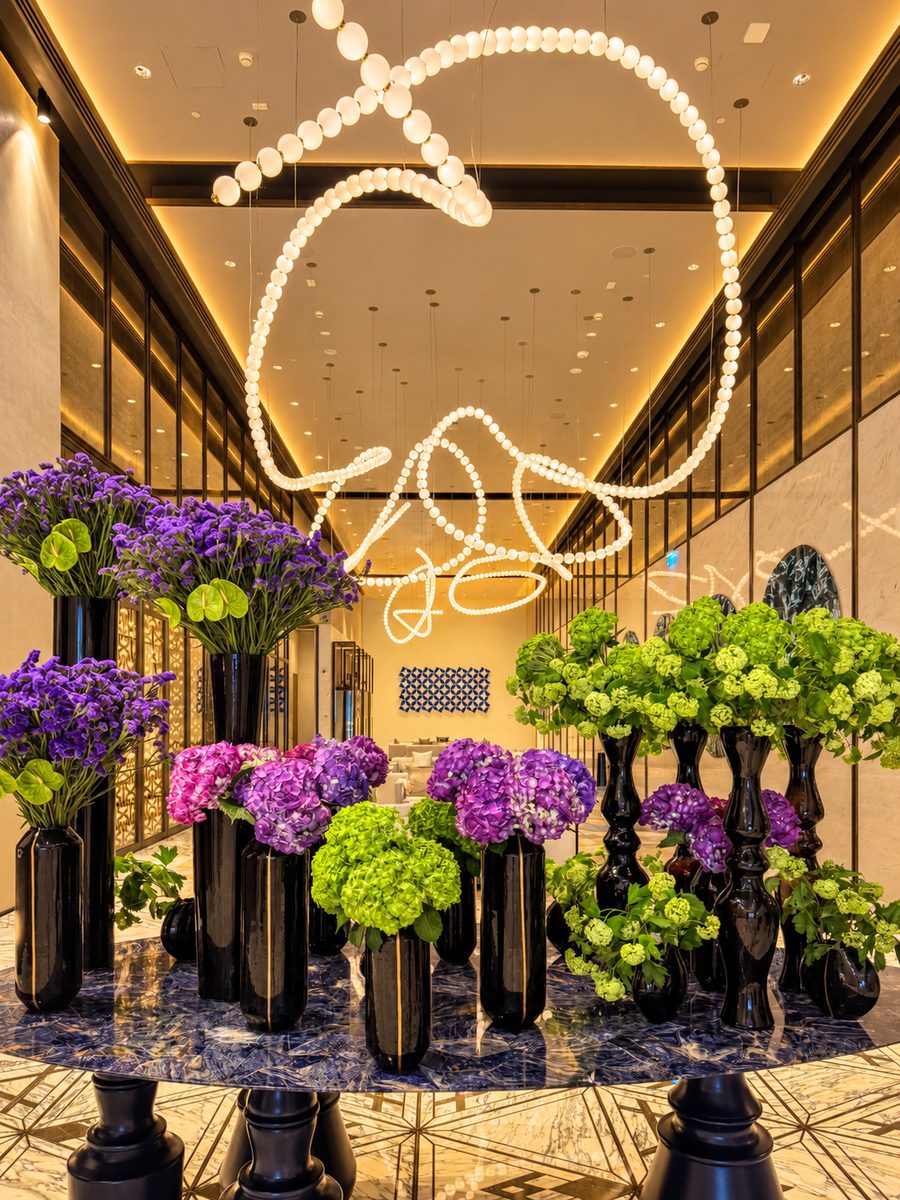 One&Only One Za’abeel, a looping pearl light sculpture above a table of hydrangeas in black vases