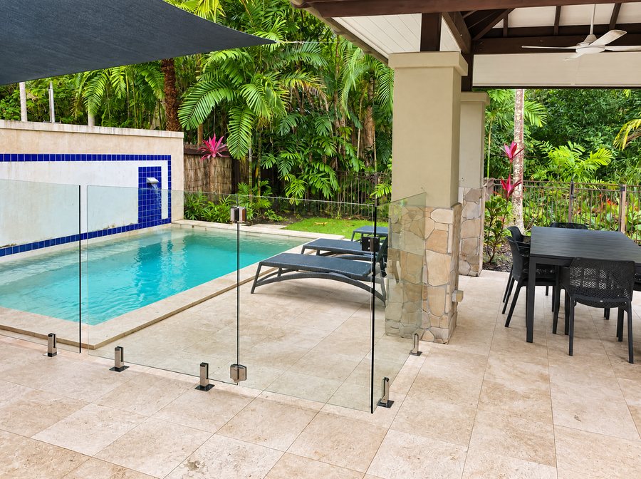 Pullman Port Douglas Sea Temple Resort & Spa, private plunge pool behind a glass fence, sun loungers and an outdoor dining table on a covered terrace, rainforest planting beyond