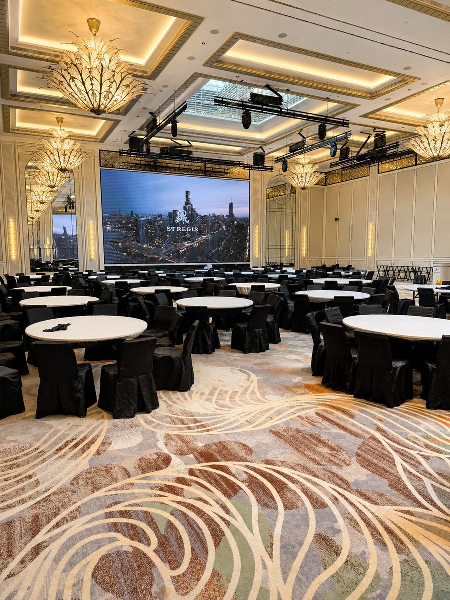 The St. Regis Singapore, a ballroom set with round tables in front of its LED wall
