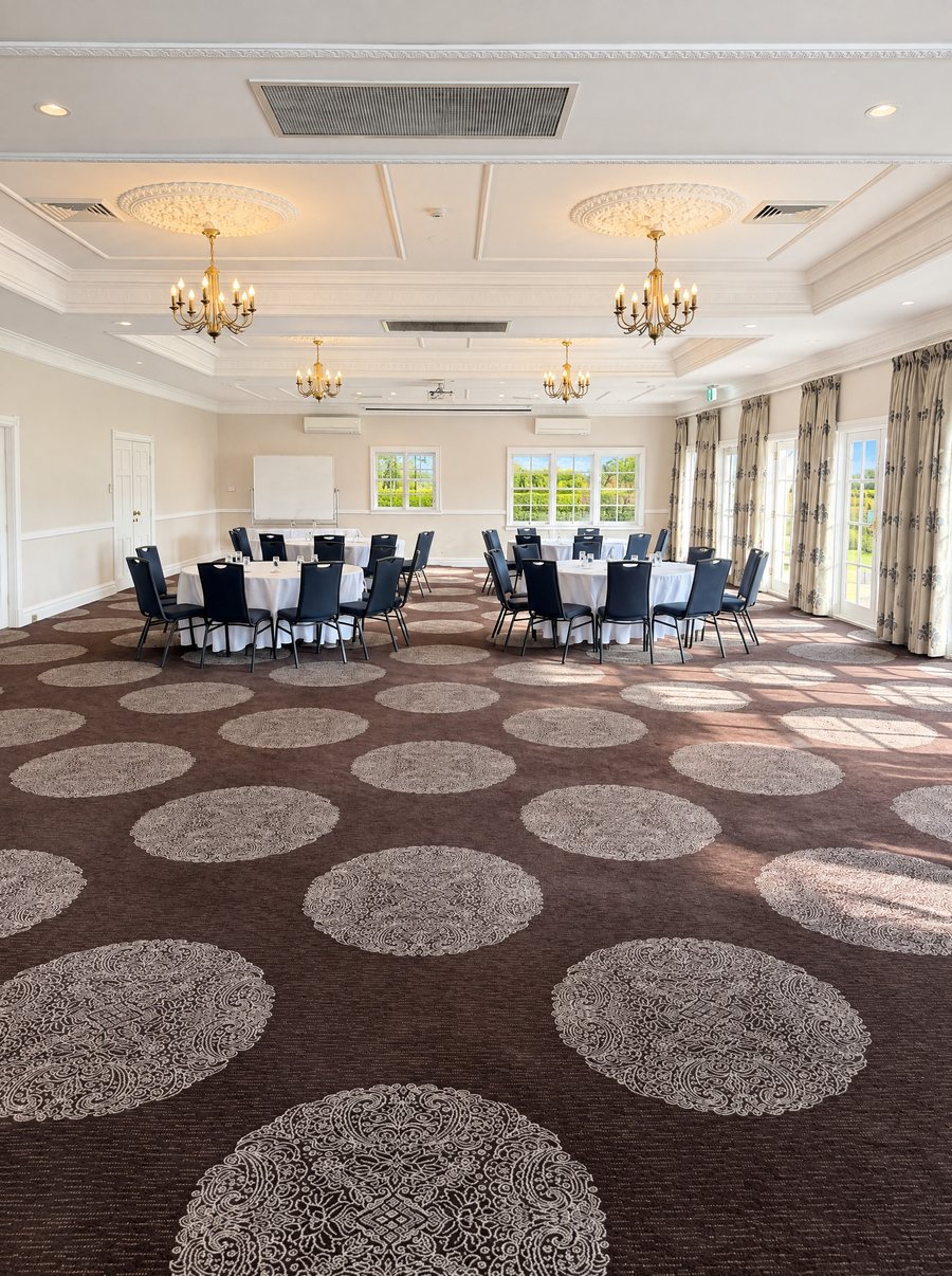voco Kirkton Park Hunter Valley, long function room under brass chandeliers, round tables in white linen at the far end, full length curtains and French doors down the right side